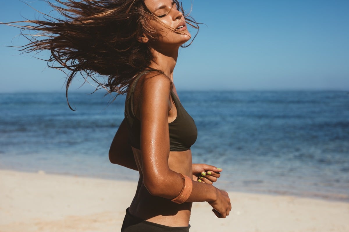Shot of young woman in bikini running on the beach. Caucasian female model on the sea shore.